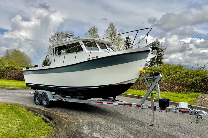 Slide: The Image of 2006 Osprey Legend boat on trailer, parked on a road with cloudy sky background. - 3