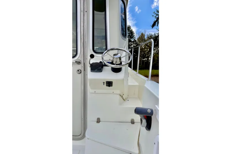 Slide: The Image of 2006 Osprey Legend boat helm with steering wheel and controls, outdoors. - 7