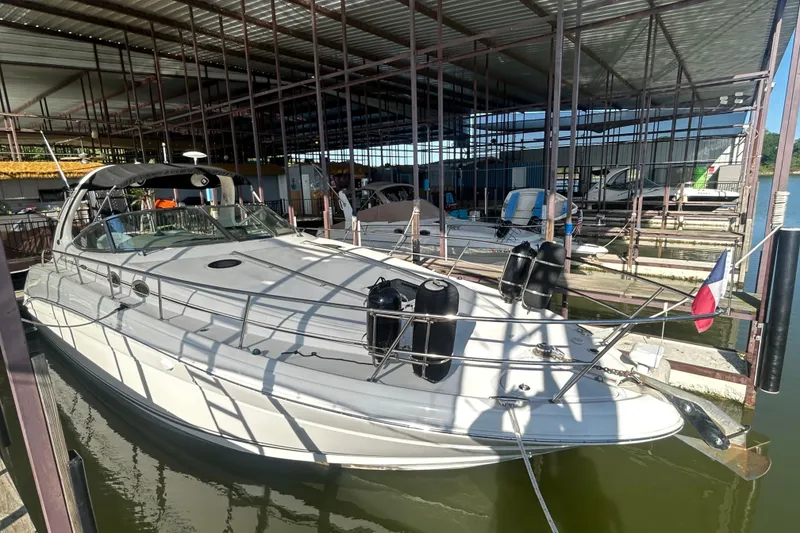 Slide: The Image of 2004 Sea Ray 360 Sundancer docked in a covered marina, featuring sleek design and white exterior. - 2