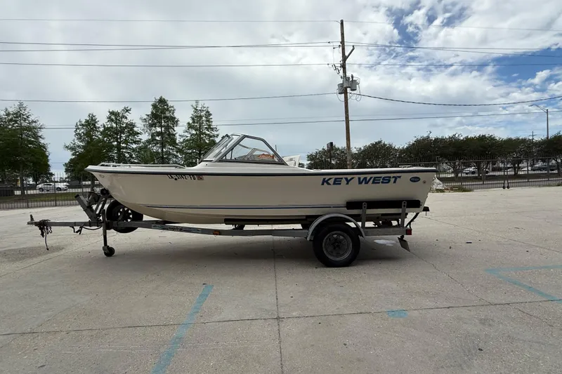 Slide: The Image of 2001 Key West 1720 Dual Console boat on trailer, parked outdoors under cloudy sky. - 6
