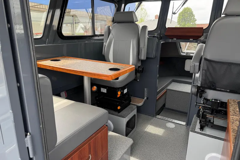 Slide: The Image of Interior of 2025 Hewescraft 240 Pacific Cruiser, featuring seating and a wooden table. - 14