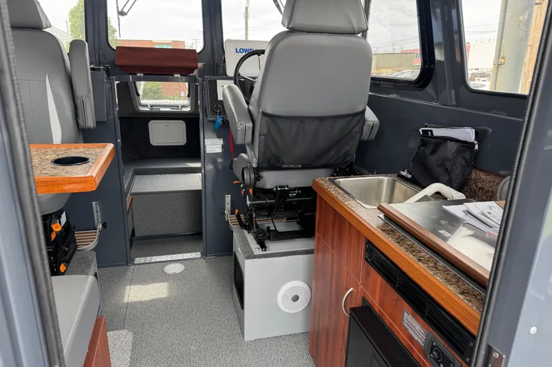 Slide: The Image of Interior of 2025 Hewescraft 240 Pacific Cruiser, featuring seating, sink, and navigation area. - 15