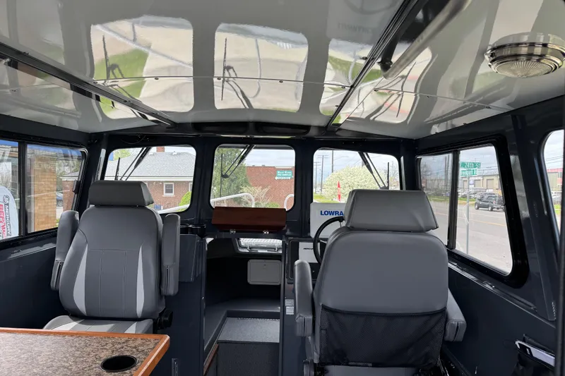 Slide: The Image of Interior of 2025 Hewescraft 240 Pacific Cruiser, featuring modern seating and navigation equipment. - 16