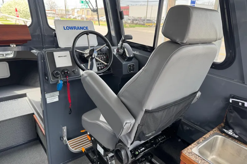 Slide: The Image of 2025 Hewescraft 240 Pacific Cruiser interior with steering wheel and navigation equipment. - 18