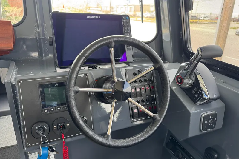 Slide: The Image of Helm of 2025 Hewescraft 240 Pacific Cruiser with steering wheel and navigation controls. - 20