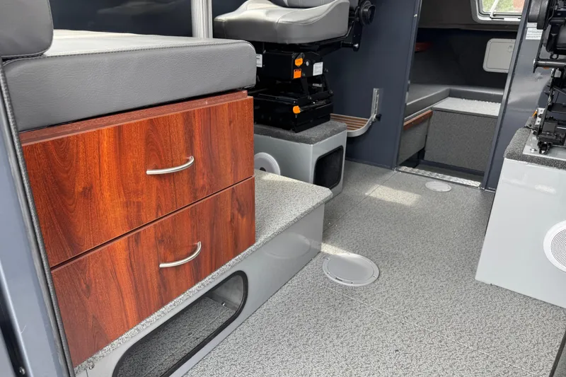 Slide: The Image of Interior of 2025 Hewescraft 240 Pacific Cruiser with wood drawers and seating. - 26