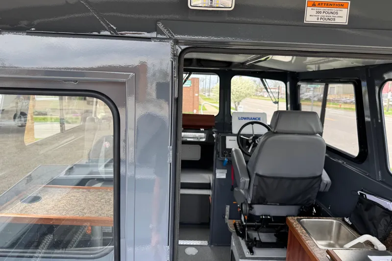 Slide: The Image of Interior of 2025 Hewescraft 240 Pacific Cruiser, featuring steering console and seating. - 32