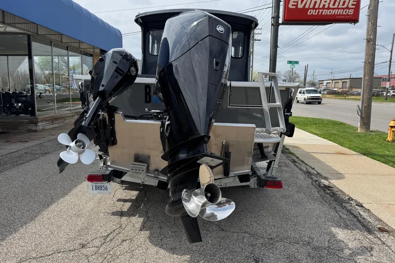 Slide: The Image of 2025 Hewescraft 240 Pacific Cruiser with dual outboard motors, parked outside dealership. - 5