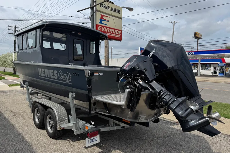 Slide: The Image of 2025 Hewescraft 240 Pacific Cruiser boat on trailer, parked near a marine store. - 7