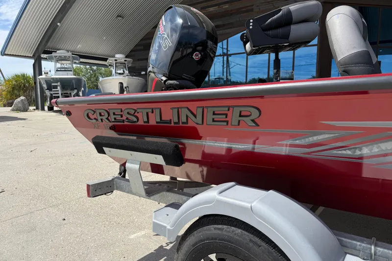 Slide: The Image of 2023 Crestliner 1850 SC boat in red, parked on a trailer outside a showroom. - 13