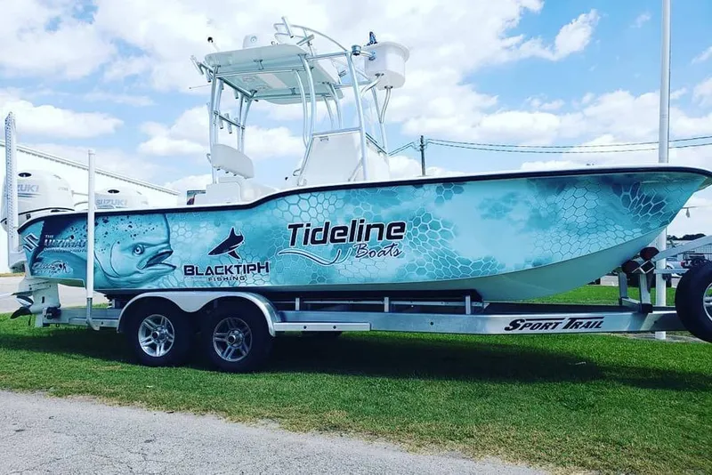 Slide: The Image of 2026 Tideline 235 Hybrid boat on trailer, featuring blue fish-themed graphics. - 10
