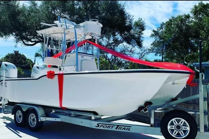 Slide: The Image of 2026 Tideline 235 Hybrid boat on trailer, adorned with red ribbon, outdoors. - 9