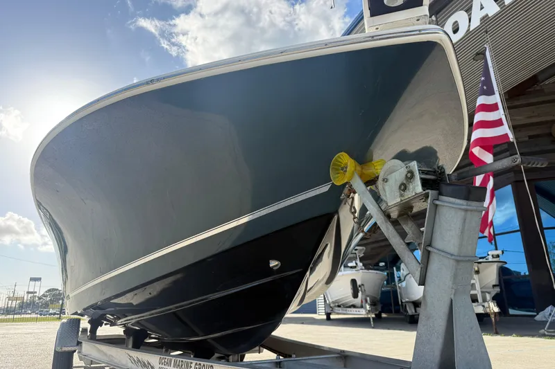 Slide: The Image of 2021 Tidewater 2500 Carolina Bay boat on trailer, with American flag, under sunny sky. - 5