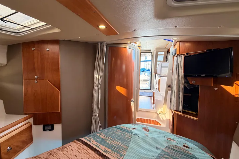 Slide: The Image of 2021 Cutwater C-32 CB cabin interior with nautical-themed bedding and wood accents. - 61