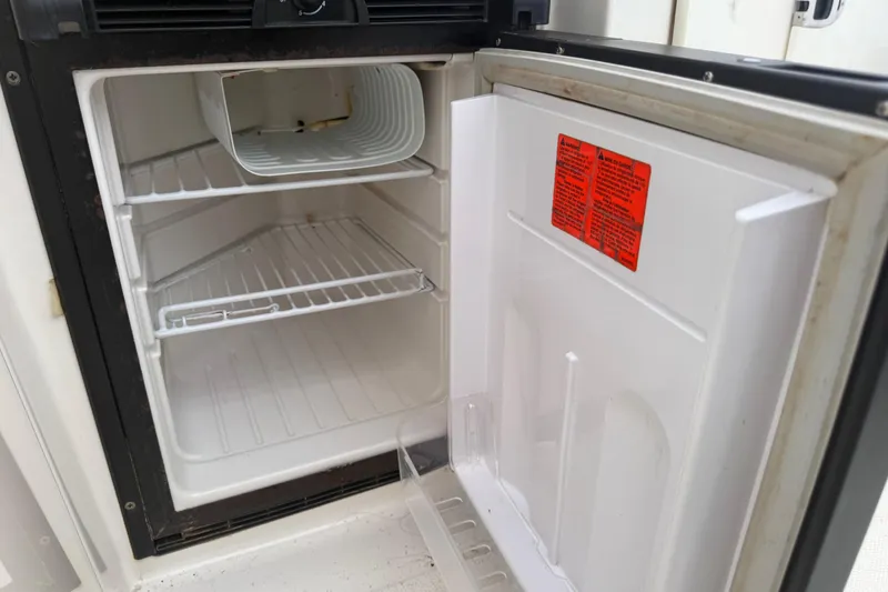 Slide: The Image of Open refrigerator inside a 2012 Sea Ray Sundancer 310 boat, showing empty shelves. - 13