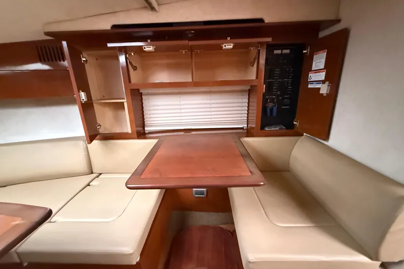 Slide: The Image of Interior of 2012 Sea Ray Sundancer 310, featuring beige seating and wooden cabinetry. - 23
