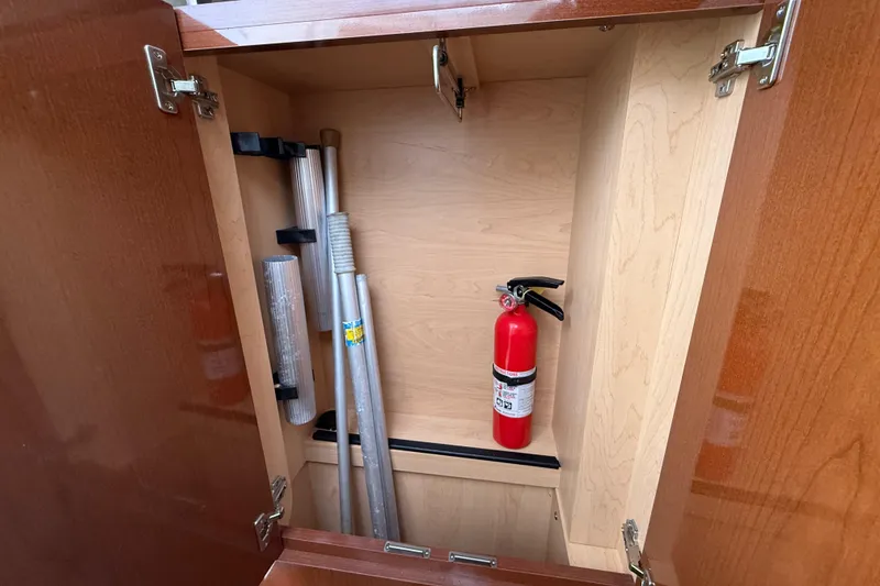 Slide: The Image of Open cabinet on 2012 Sea Ray Sundancer 310 with fire extinguisher and metal poles. - 26