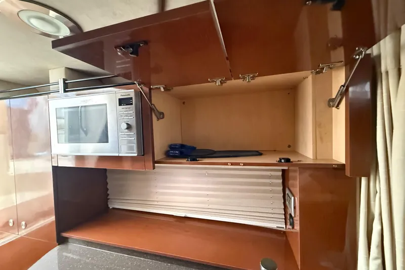 Slide: The Image of Interior of 2012 Sea Ray Sundancer 310 with microwave and open storage cabinets. - 27