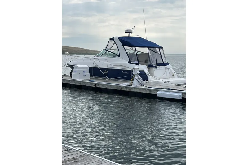 Slide: The Image of 2005 Cruisers Yachts 370 Express docked on calm water under cloudy sky. - 2