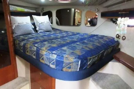 Slide: The Image of 2005 Cruisers Yachts 370 Express cabin with a patterned bedspread and cozy interior. - 23