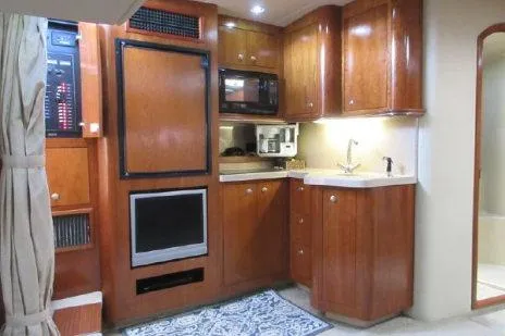 Slide: The Image of 2005 Cruisers Yachts 370 Express interior kitchen with wood cabinetry and modern appliances. - 24