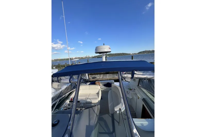 Slide: The Image of 2005 Cruisers Yachts 370 Express docked, featuring blue canopy and scenic waterfront view. - 7