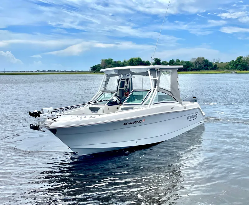 Slide: The Image of 2023 Robalo R247 Dual Console boat on calm water. - 2