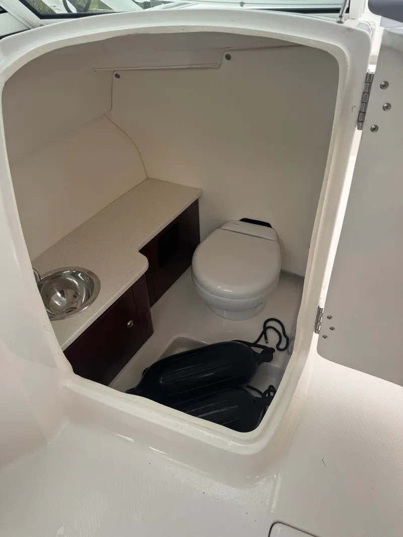 Slide: The Image of Interior of 2023 Robalo R247 Dual Console with toilet and sink. - 23