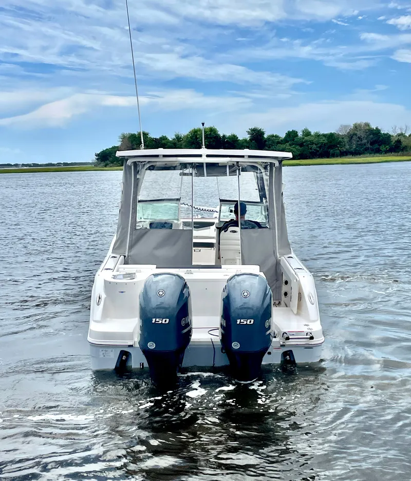 Slide: The Image of 2023 Robalo R247 Dual Console on calm water with twin outboard engines. - 7