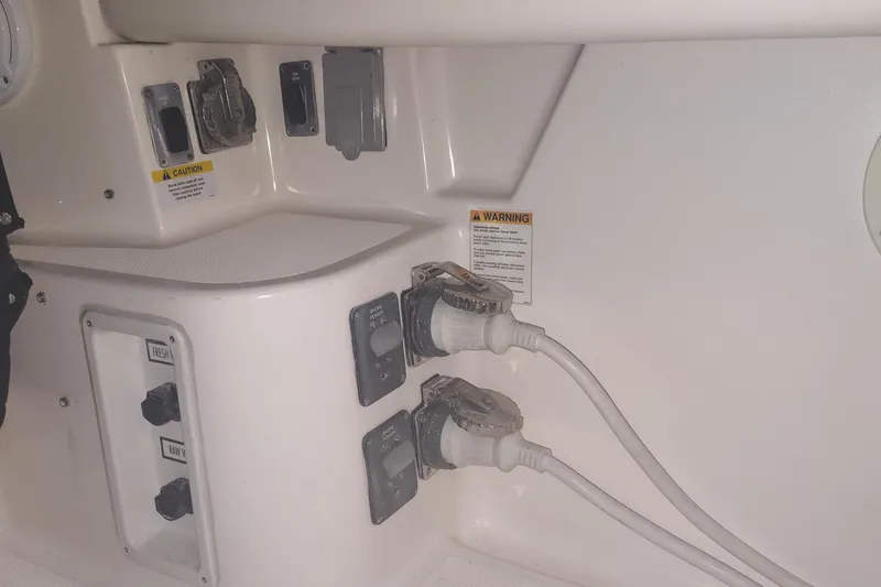 Slide: The Image of 2003 Tiara Yachts 3100 Open LE electrical panel with power connections and warning labels. - 24