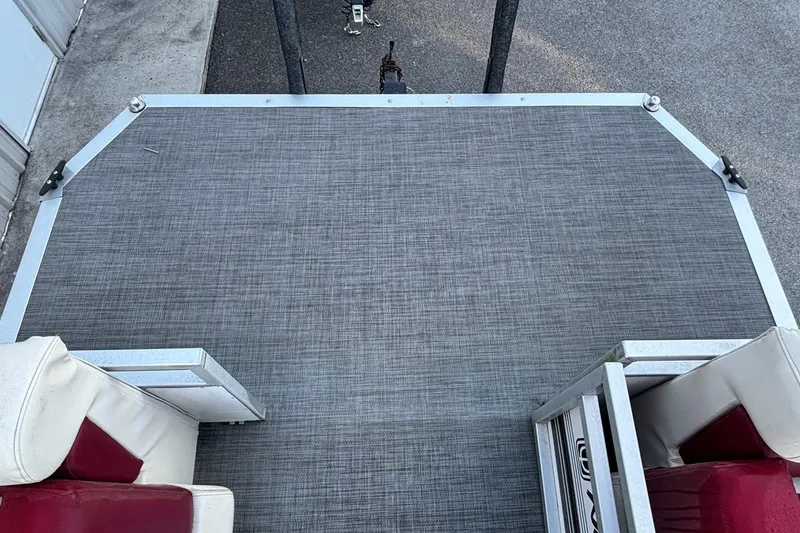 Slide: The Image of Pontoon boat deck with gray flooring, red and white seating, JC Manufacture 24 Dolphin, 2000 model. - 2