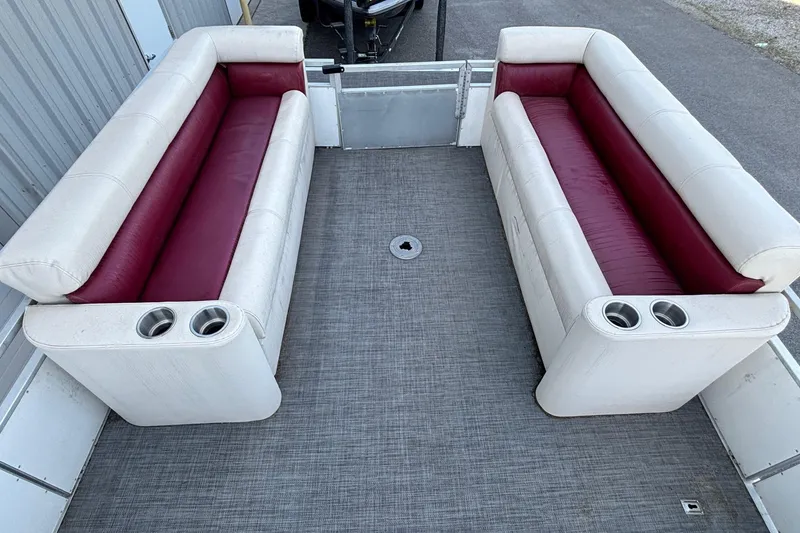 Slide: The Image of Pontoon boat interior with white and maroon seating, cup holders, and gray flooring. JC Manufacture 24 Dolphin, 2000. - 3