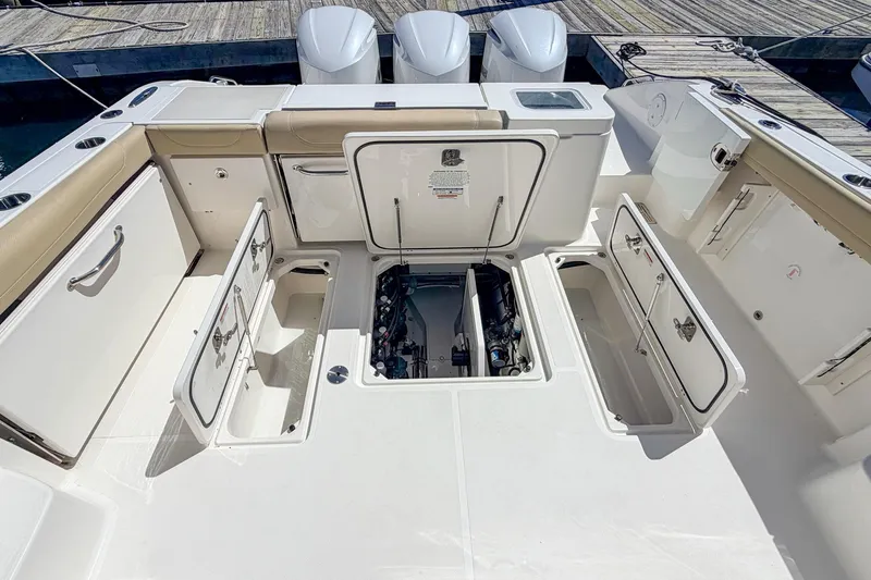 Slide: The Image of 2020 Pursuit OS 355 Offshore boat deck with open storage compartments and engine access. - 10