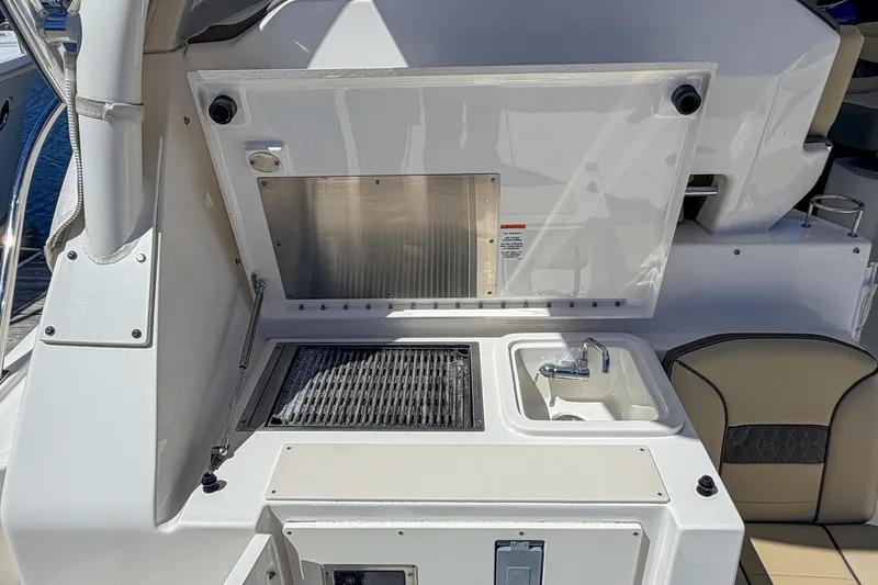Slide: The Image of Outdoor kitchen area on a 2020 Pursuit OS 355 Offshore boat, featuring a grill and sink. - 14