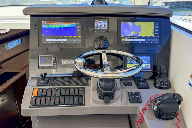 Slide: The Image of Control panel of 2020 Pursuit OS 355 Offshore boat with navigation screens and steering wheel. - 16