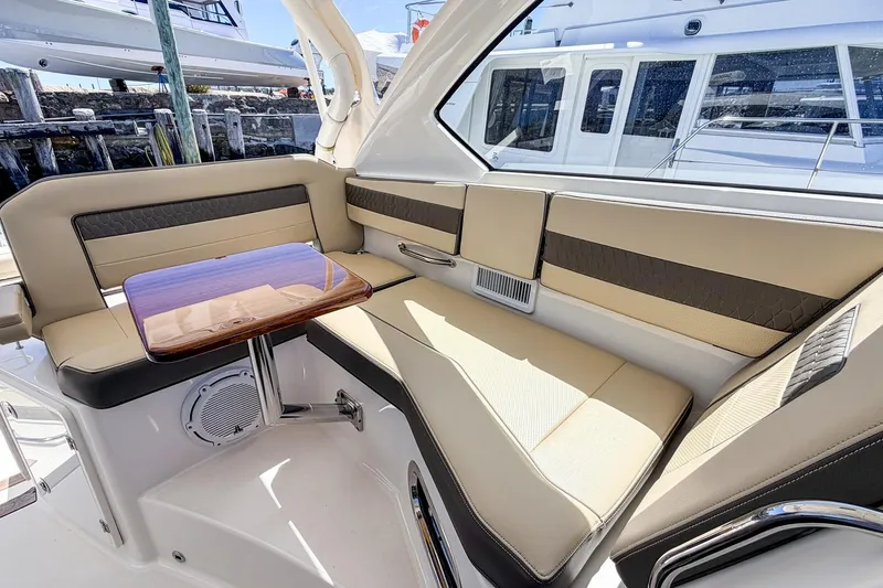 Slide: The Image of 2020 Pursuit OS 355 Offshore boat interior with beige seating and wooden table. - 21