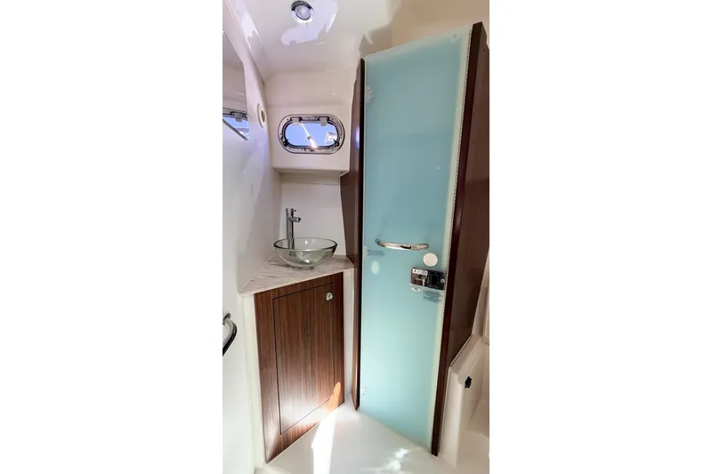 Slide: The Image of 2020 Pursuit OS 355 Offshore bathroom with glass sink and frosted door. - 26