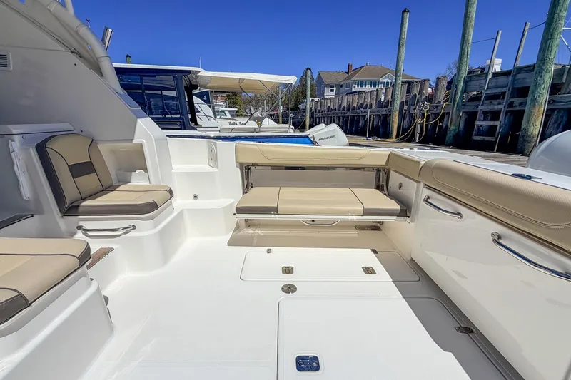 Slide: The Image of 2020 Pursuit OS 355 Offshore boat interior with beige seating and dockside view. - 6
