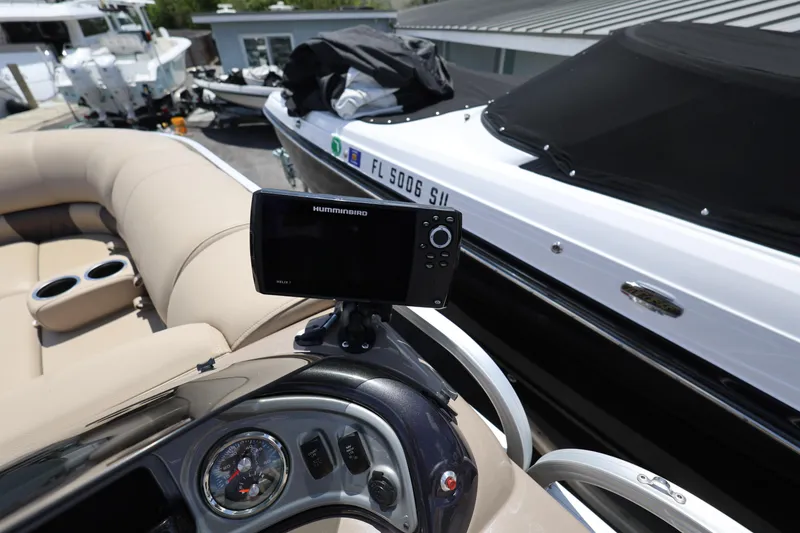 Slide: The Image of 2023 SUNTRACKER PB 22DLX boat interior with Humminbird navigation system and beige seating. - 23