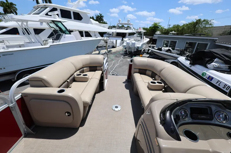 Slide: The Image of 2023 SUNTRACKER PB 22DLX pontoon boat interior with beige seating and dashboard. - 24