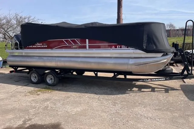 Slide: The Image of 2023 SUNTRACKER PB 22DLX pontoon boat on trailer, covered, parked outdoors. - 28
