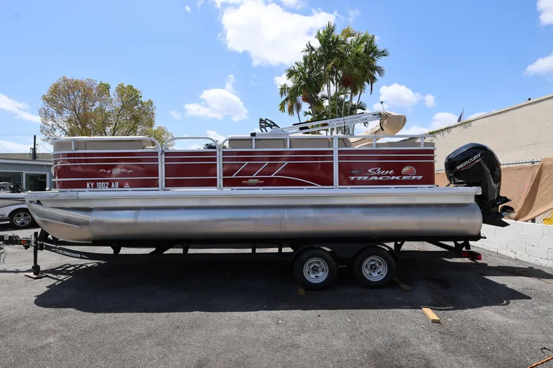 Slide: The Image of 2023 SUNTRACKER PB 22DLX pontoon boat on trailer, parked outdoors. - 3