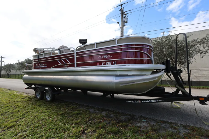 Slide: The Image of 2023 SUNTRACKER PB 22DLX pontoon boat on trailer, parked roadside. - 5