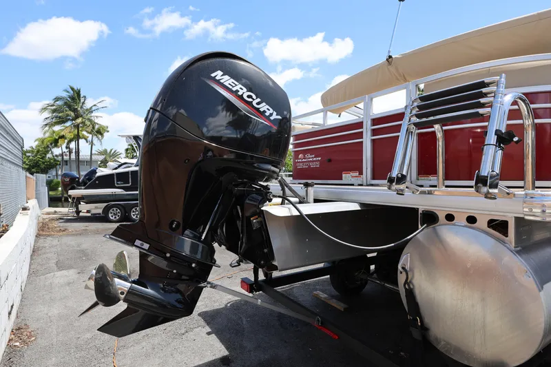 Slide: The Image of 2023 SUNTRACKER PB 22DLX pontoon boat with Mercury outboard motor, parked outdoors. - 7
