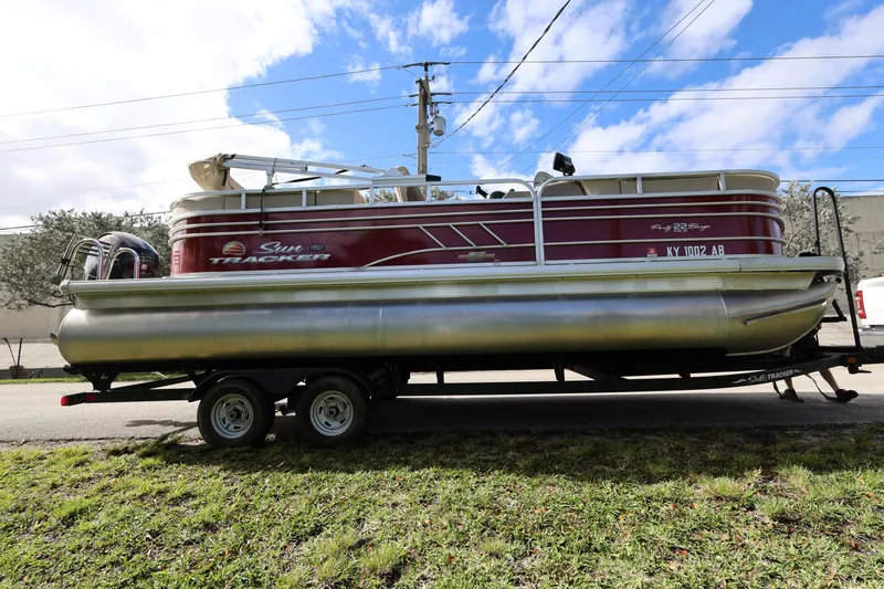 Slide: The Image of 2023 SUNTRACKER PB 22DLX pontoon boat on trailer, parked outdoors. - 8
