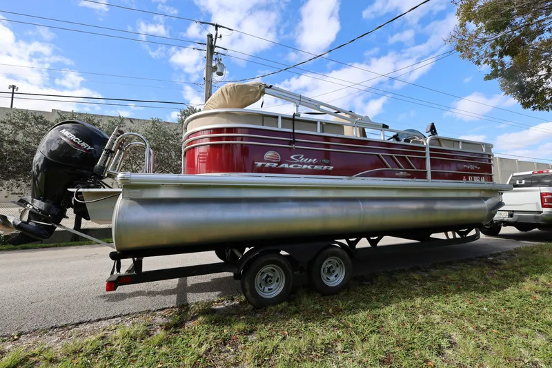 Slide: The Image of 2023 SUNTRACKER PB 22DLX pontoon boat on trailer, parked outdoors. - 9