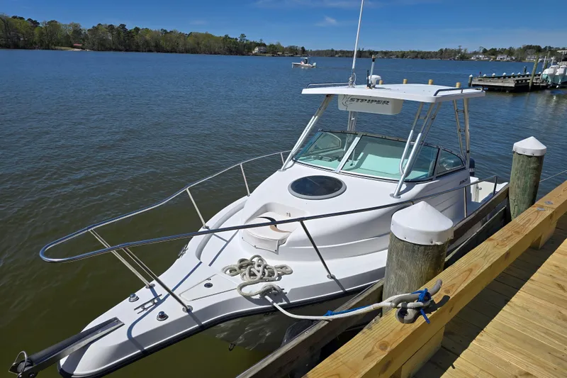 Slide: The Image of 2003 Seaswirl Striper 2301 Walkaround OB docked by a wooden pier on a sunny day. - 12