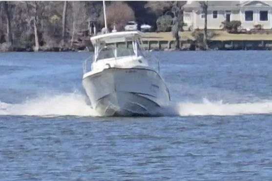 Slide: The Image of 2003 Seaswirl Striper 2301 Walkaround OB cruising on a lake with shoreline in background. - 3