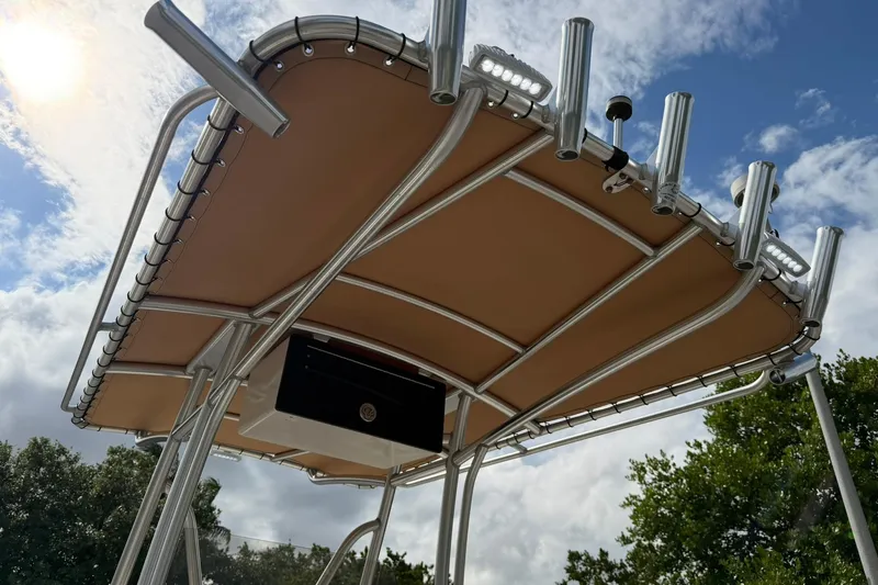 Slide: The Image of 2017 Pioneer 202 Islander boat canopy with rod holders under a partly cloudy sky. - 16