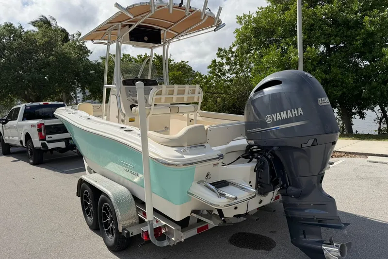 Slide: The Image of 2017 Pioneer 202 Islander boat with Yamaha engine on trailer, parked near trees. - 5